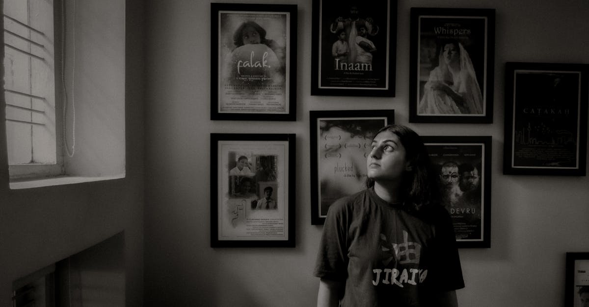 Siyah-beyaz fotoğrafta, bir kişi çeşitli film posterlerinin asılı olduğu duvarın önünde yukarıya bakıyor. Posterler arasında "Palak".